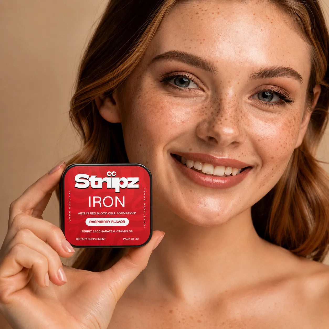 Woman holding a red supplement container labeled 'Iron Striipz' against a beige background
