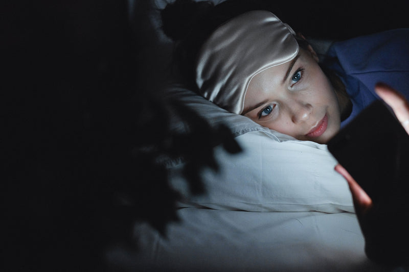 Person lying in bed using a smartphone in the dark