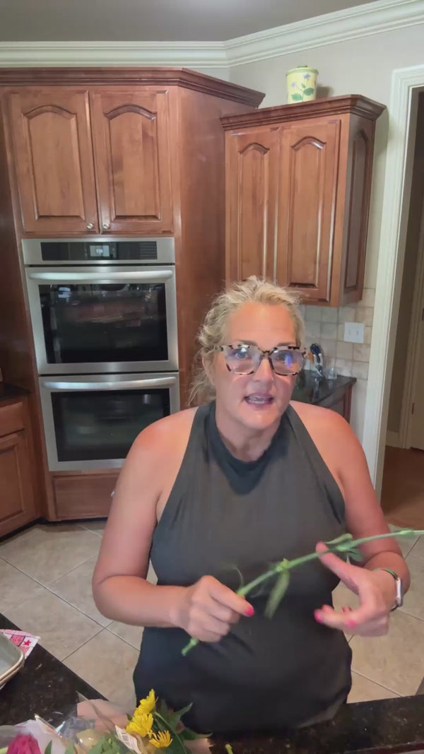 Woman showcasing Striipz Gut Health dietary supplement strips and taking a wellness strip in her kitchen