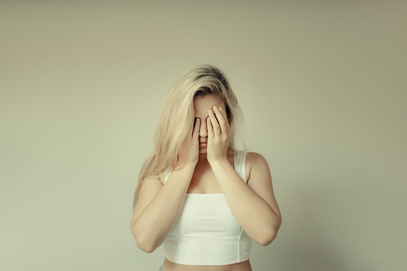 Woman covering her face with her hands, representing stress, fatigue, or feeling overwhelmed